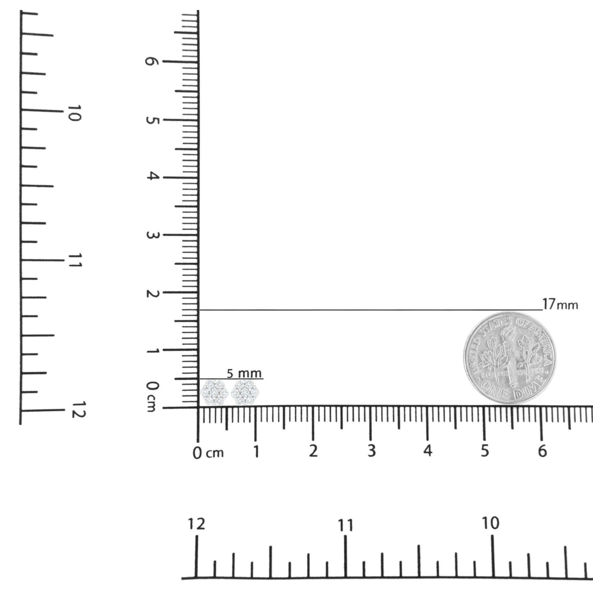 Top-down view of a pair of white metal stud earrings with round white gemstones in prong settings, displayed on a ruler for size reference.