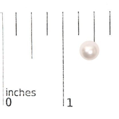 Single round white gemstone earring on a ruler for size reference, top-down angle.