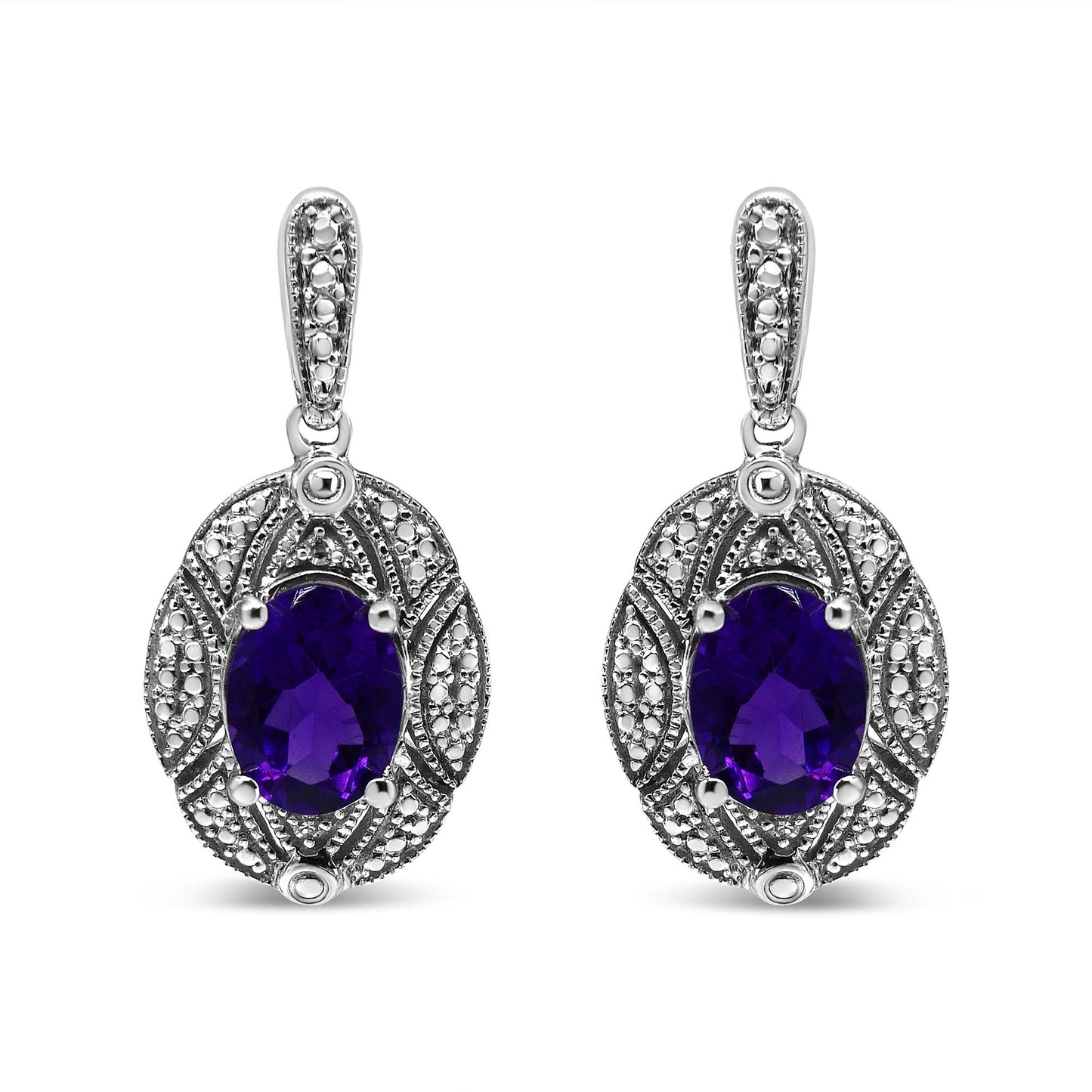 Front view of white metal drop earrings with oval purple gemstones surrounded by intricate detailing with small round white gemstones in prong settings.