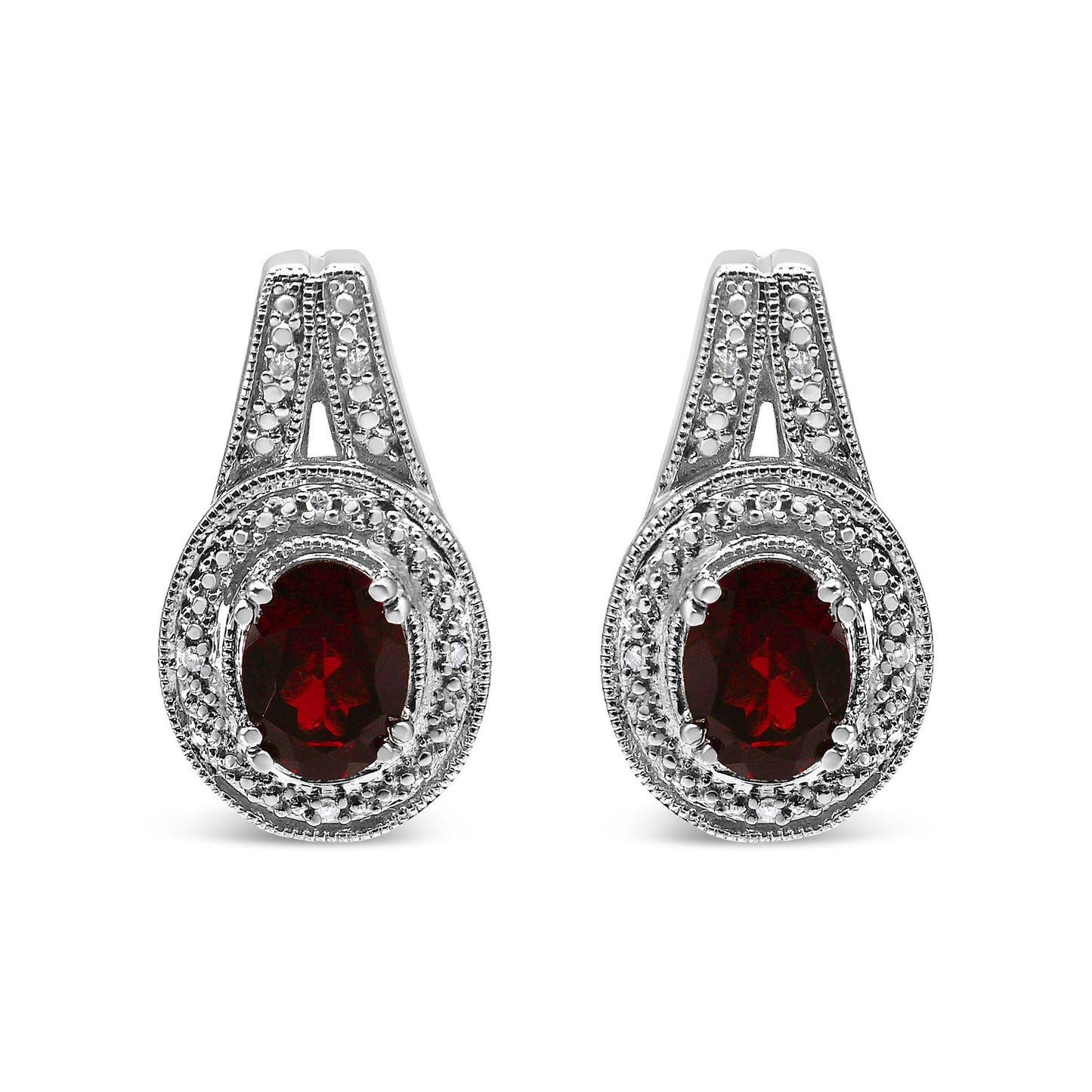 Front view of white metal earrings with oval red gemstones surrounded by multiple round white gemstones in prong settings.