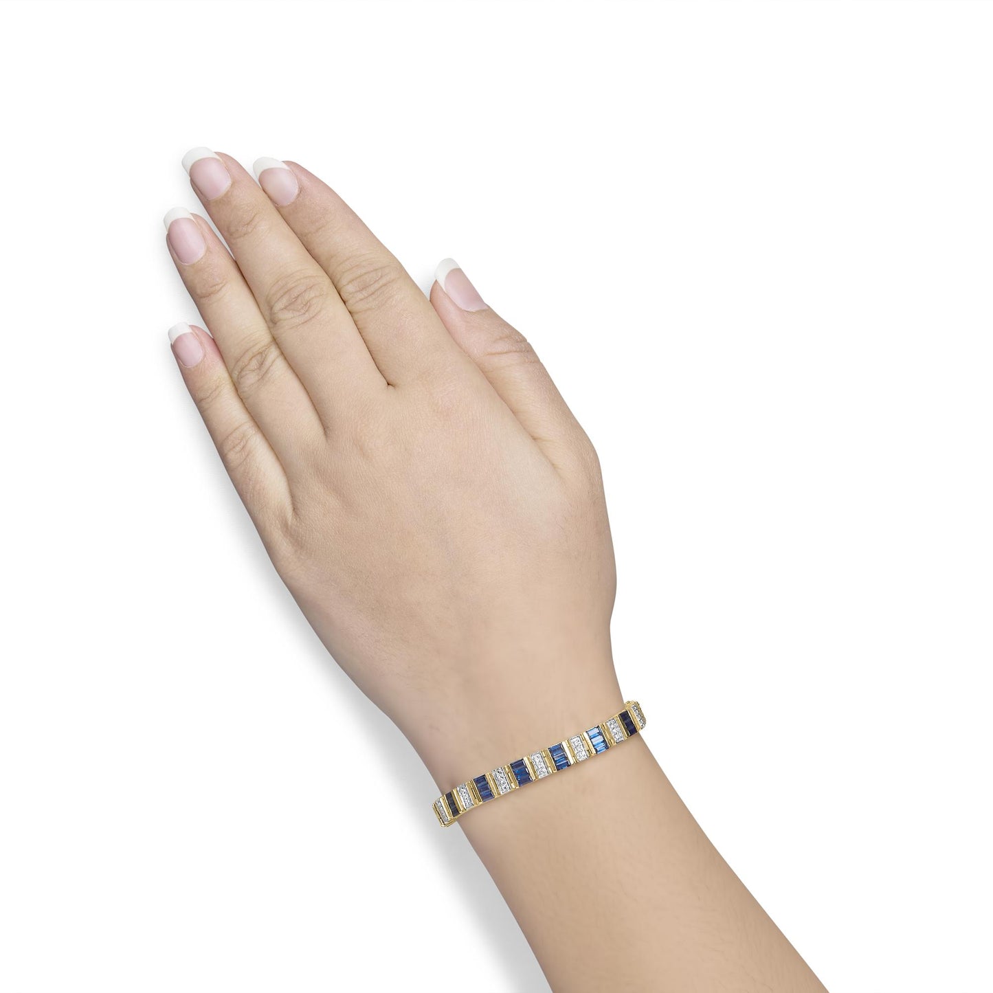 Yellow metal bracelet with alternating blue baguette-shaped gemstones and white round-shaped gemstones, shown worn on a model's wrist, angled view.