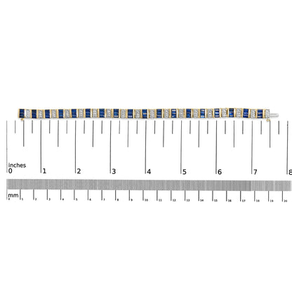 Top-down view of a yellow bracelet with alternating blue baguette-shaped gemstones and white round-shaped gemstones set in a linear pattern, placed on a ruler for size reference.