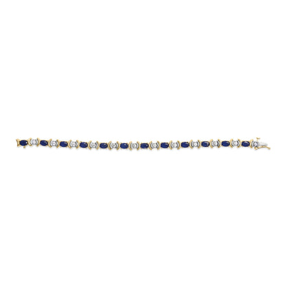 Yellow metal bracelet with alternating oval blue gemstones and round white gemstones, shot from above on a white background.
