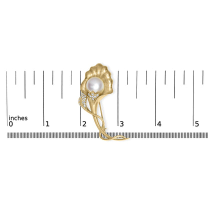 Yellow metal floral brooch with a central round white gemstone and pave set white gemstones along the stem, shown from the front on a ruler for size reference.