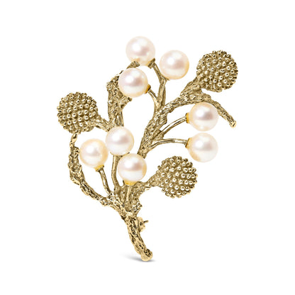 Front angled view of a yellow metal brooch shaped like textured branches with clusters of round white pearls and spherical textured elements.