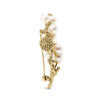 Side view of a yellow metal brooch featuring round white pearls and textured yellow metal design.
