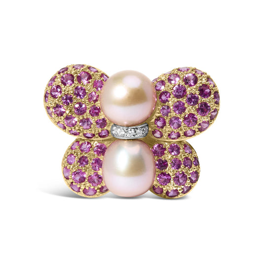 Front-facing close-up of a butterfly-shaped brooch with yellow and white metal, adorned with pink round gemstones in pave setting on the wings, two pearls as the body, and a small strip of white metal with white round gemstones in pave setting between the pearls.