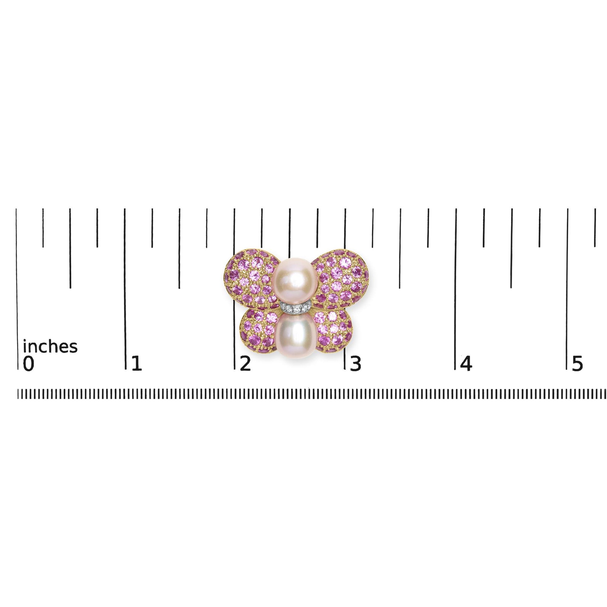 Brooch shaped like a butterfly with pink gemstones and white gemstones on yellow and white metal, photographed from above on a ruler for size reference.