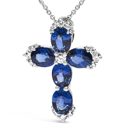 Close-up front view of a white metal cross-shaped necklace pendant featuring oval blue gemstones and round white gemstones in shared prong settings.