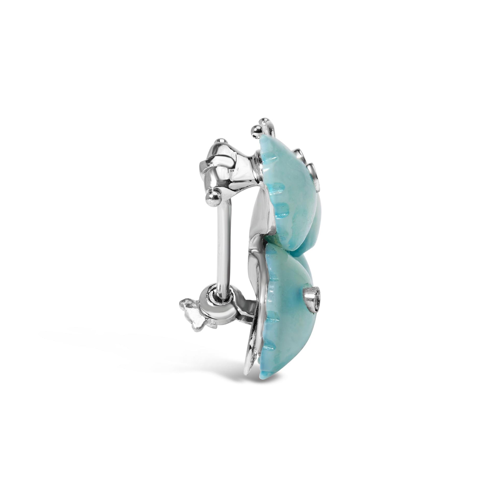 Side angle view of a white metal brooch featuring two rounded turquoise-colored stones with a central white gemstone on each. The back shows the pin clasp mechanism.