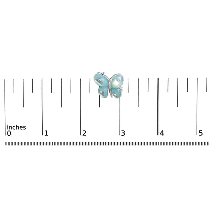 White metal butterfly-shaped brooch with blue wings accented by round white gemstones in bezel and pave settings, shown on a scale from a top-down angle.