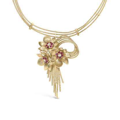 Yellow metal necklace with three floral pendants featuring red gemstones and white gemstones in the center, captured from a front angle on a white background.