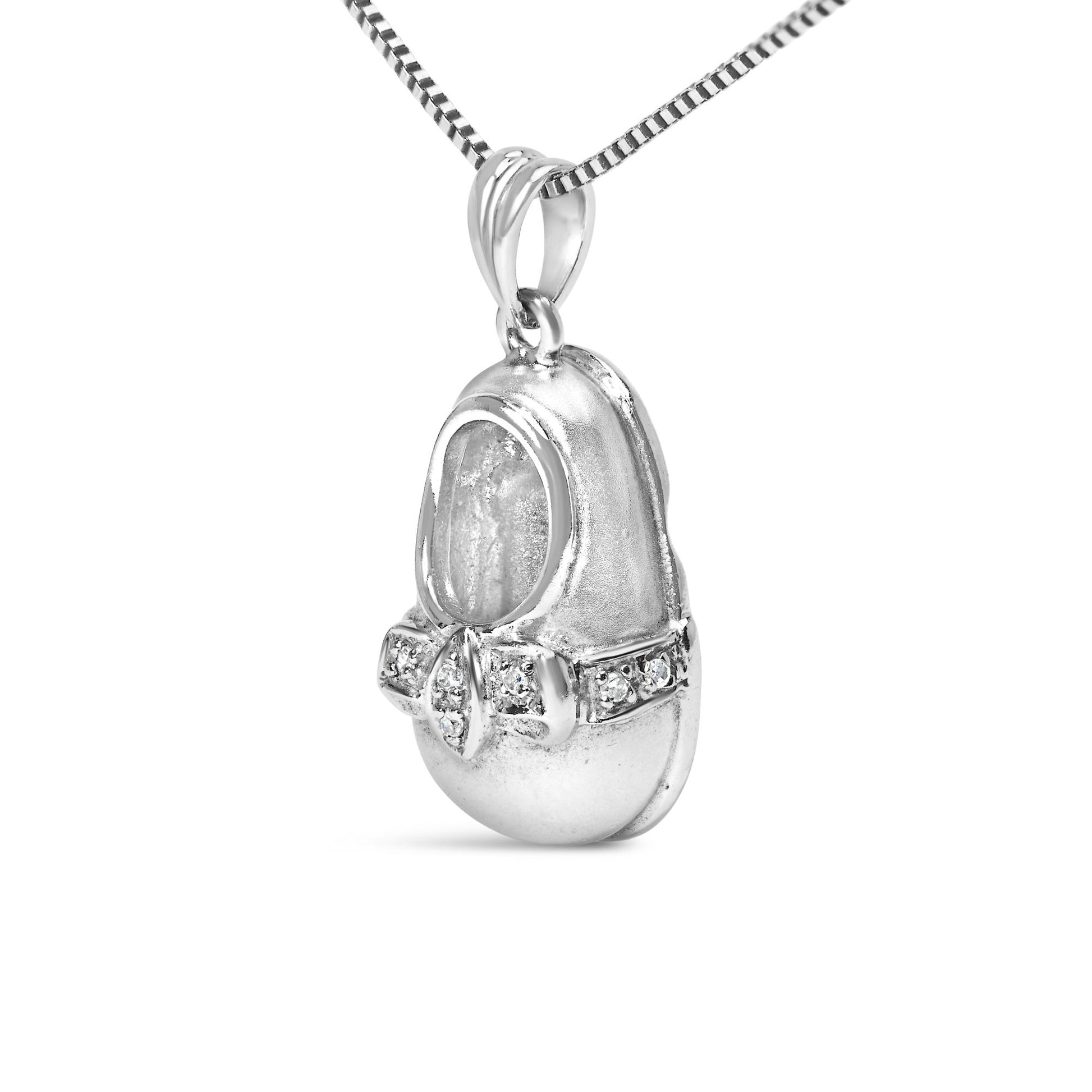 Close-up front angle of a white necklace pendant shaped like a shoe with a bow detail adorned with round white gemstones in 4-prong settings, shown on a chain.