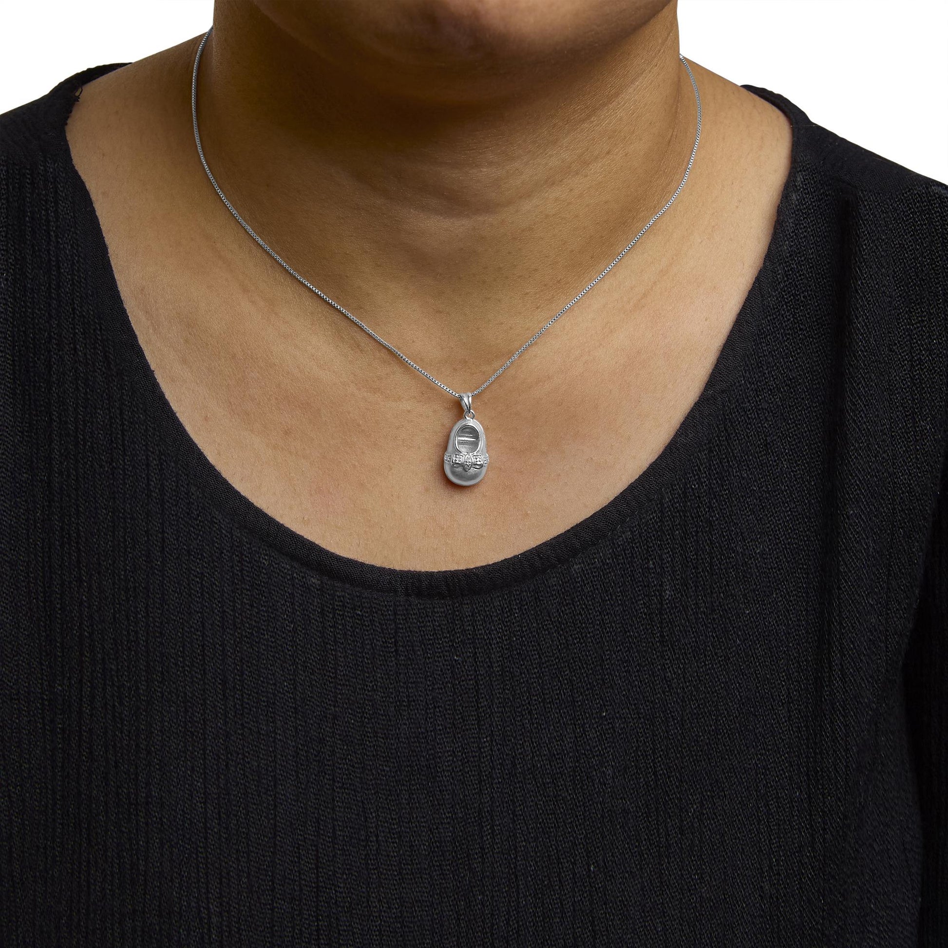 Close-up front view of a white metal necklace with a pendant featuring round white gemstones in a 4-prong setting, shown worn on a model.