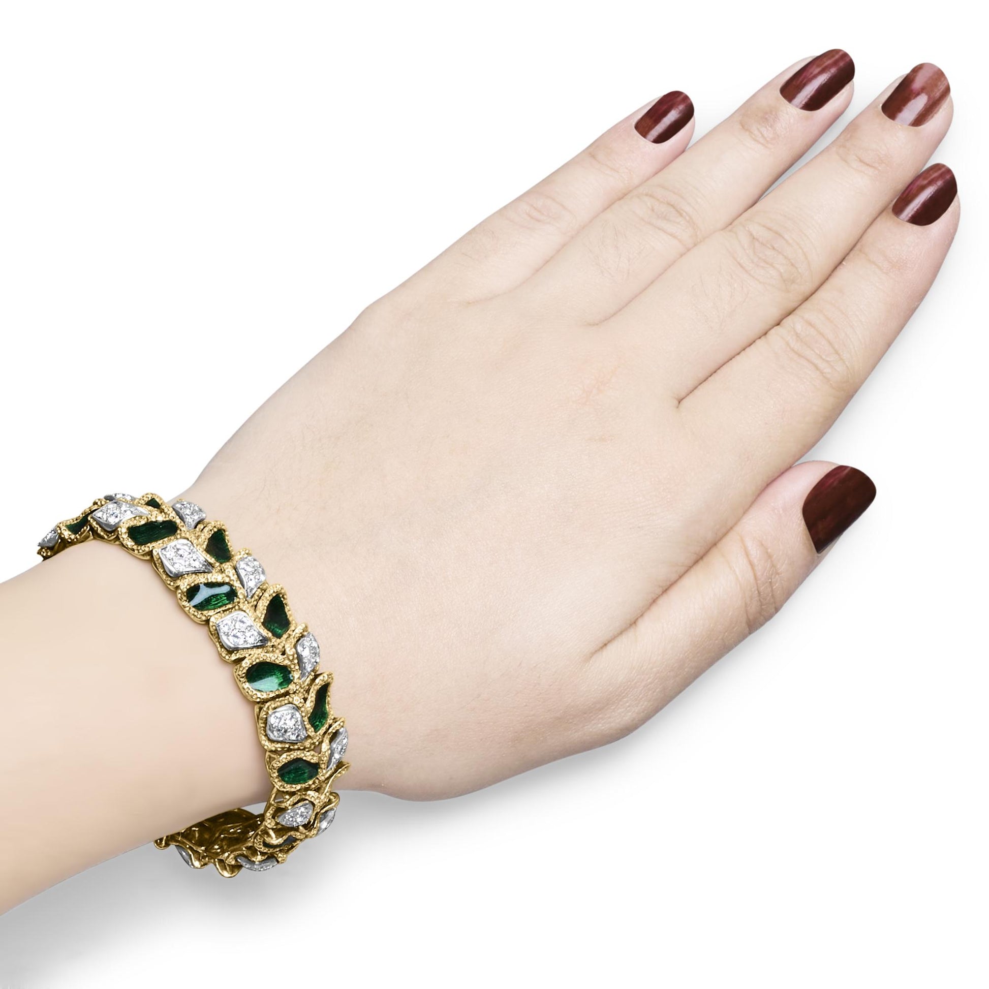 Yellow metal bracelet with pave set white gemstones and green gemstones, worn on a model's wrist, shot from above.