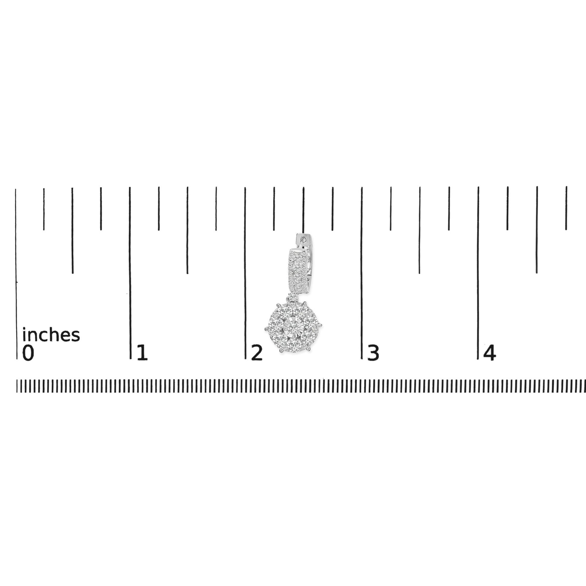 White metal earring with a round cluster of white gemstones in prong setting hanging from a rectangular section adorned with channel and prong set white gemstones, shown on a ruler scale from a front angle.