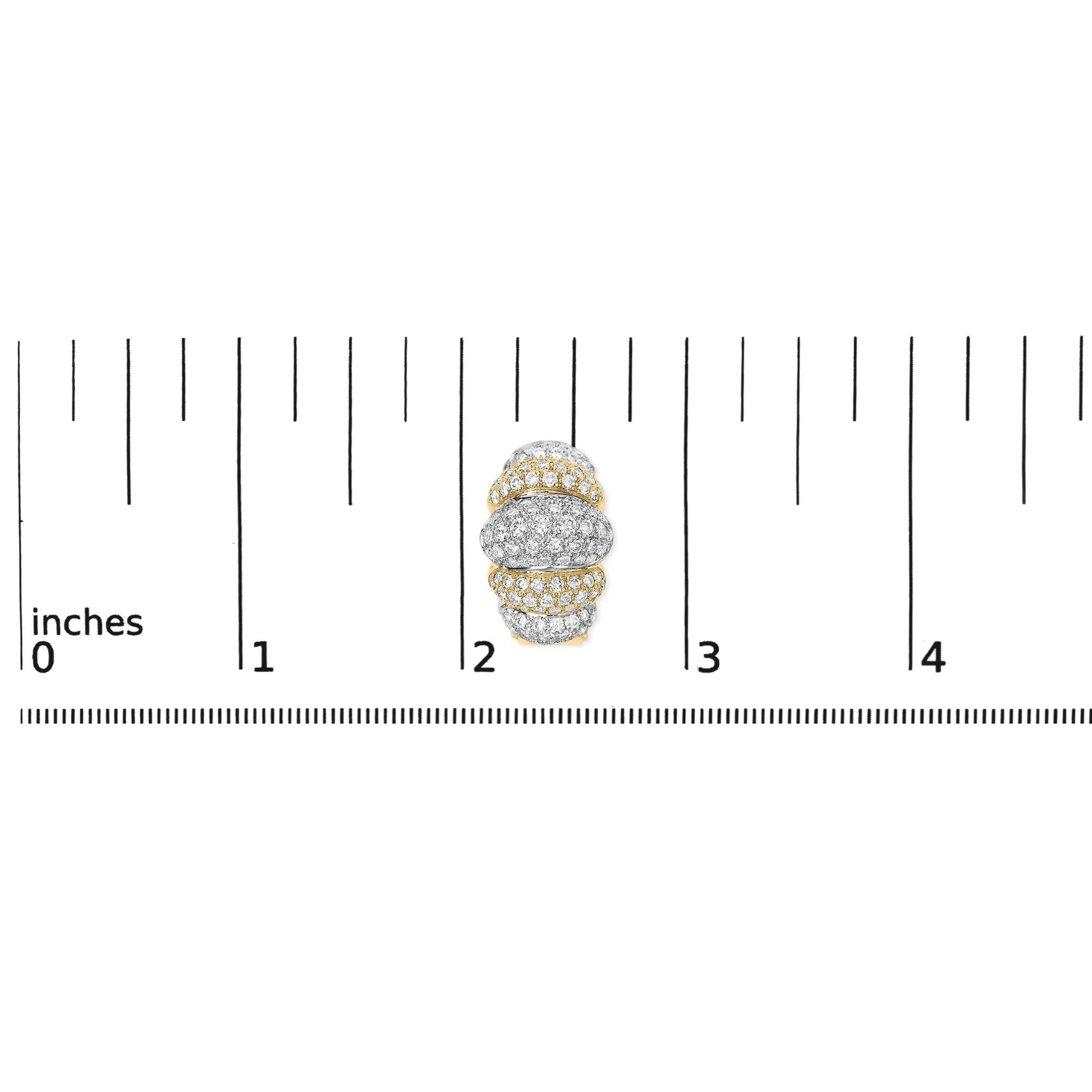 Close-up top view of a rounded earring with alternating yellow and white areas, pavé set with numerous small white gemstones, shown on a ruler for scale.