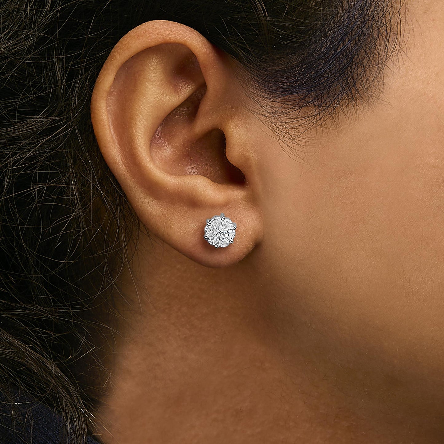 Close-up side view of a model wearing a white metal stud earring with a cluster of white pie-shaped gemstones in an invisible setting.