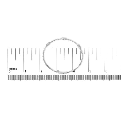 White bracelet with round white gemstones in shared prong settings, shown lying flat on a ruler for scale, top-down angle.