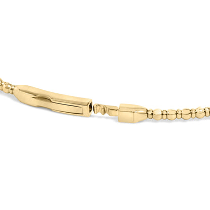 Close-up side angle of an open yellow metal bracelet clasp with rounded bead details along the band, shown on a white background.