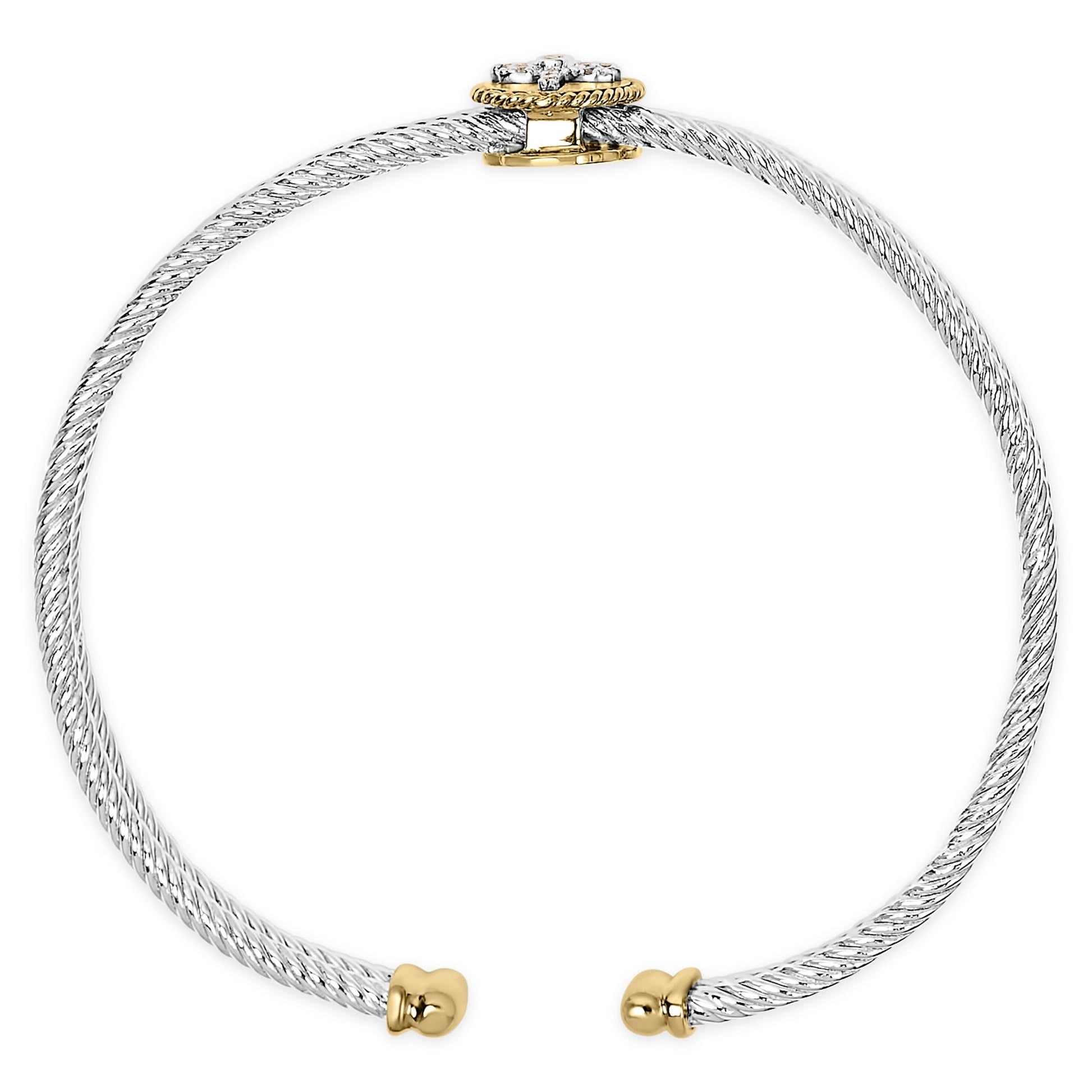 Front-facing close-up of an open twisted white metal bracelet with rounded yellow metal ends and a yellow metal clasp featuring one round bezel-set and multiple round prong-set white gemstones.