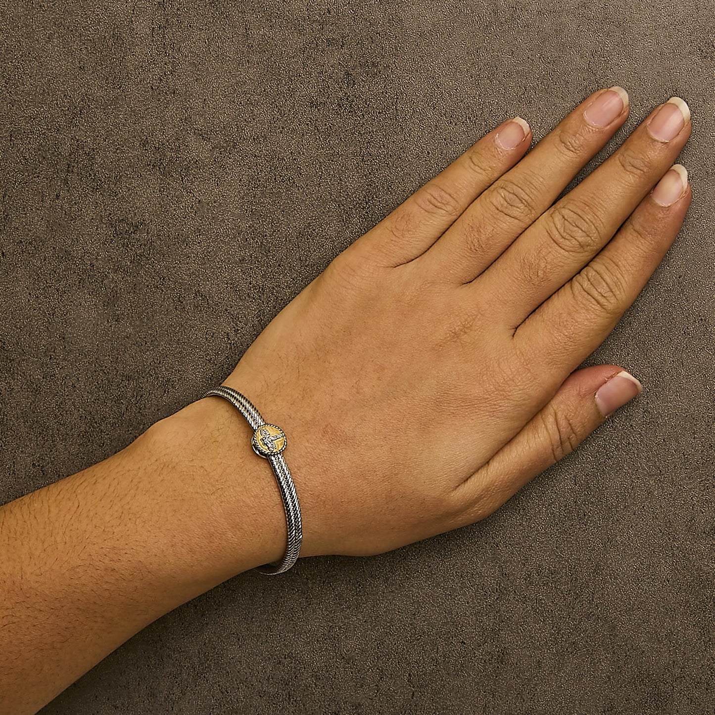 Bracelet shown worn on a model's wrist, featuring a two-tone band with a round yellow centerpiece set with one bezel-set white gemstone and multiple prong-set white gemstones, viewed from above at an angle.
