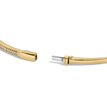 Close-up image of an open yellow bracelet with a line of small round white gemstones in prong settings along part of its length, shown at an angle on a white background.