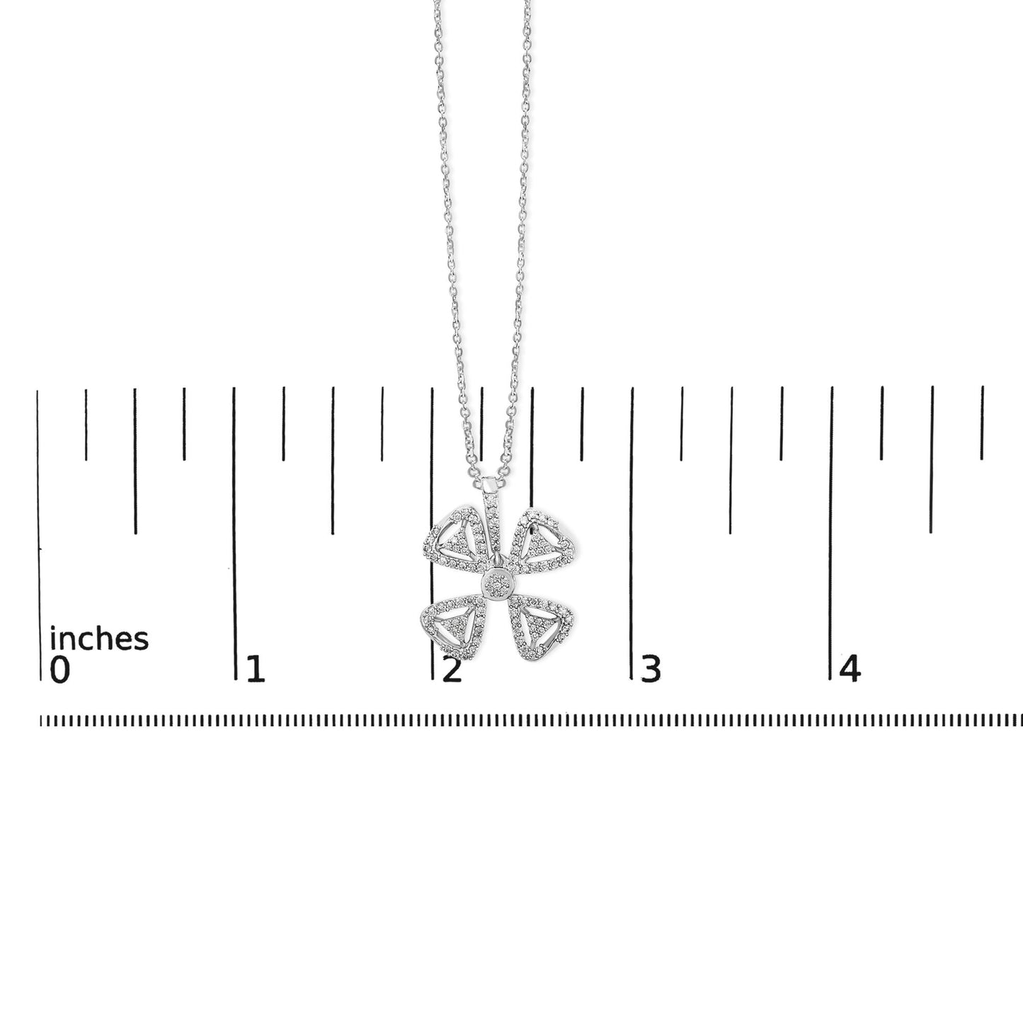 White metal necklace with a four-petal flower pendant accented with round white gemstones, shown centered on a ruler scale from a top-down angle.