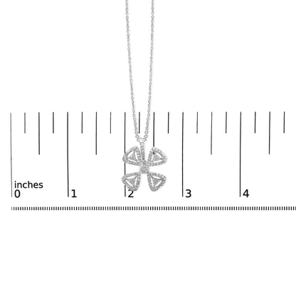 White metal necklace with a four-petal flower pendant accented with round white gemstones, shown centered on a ruler scale from a top-down angle.