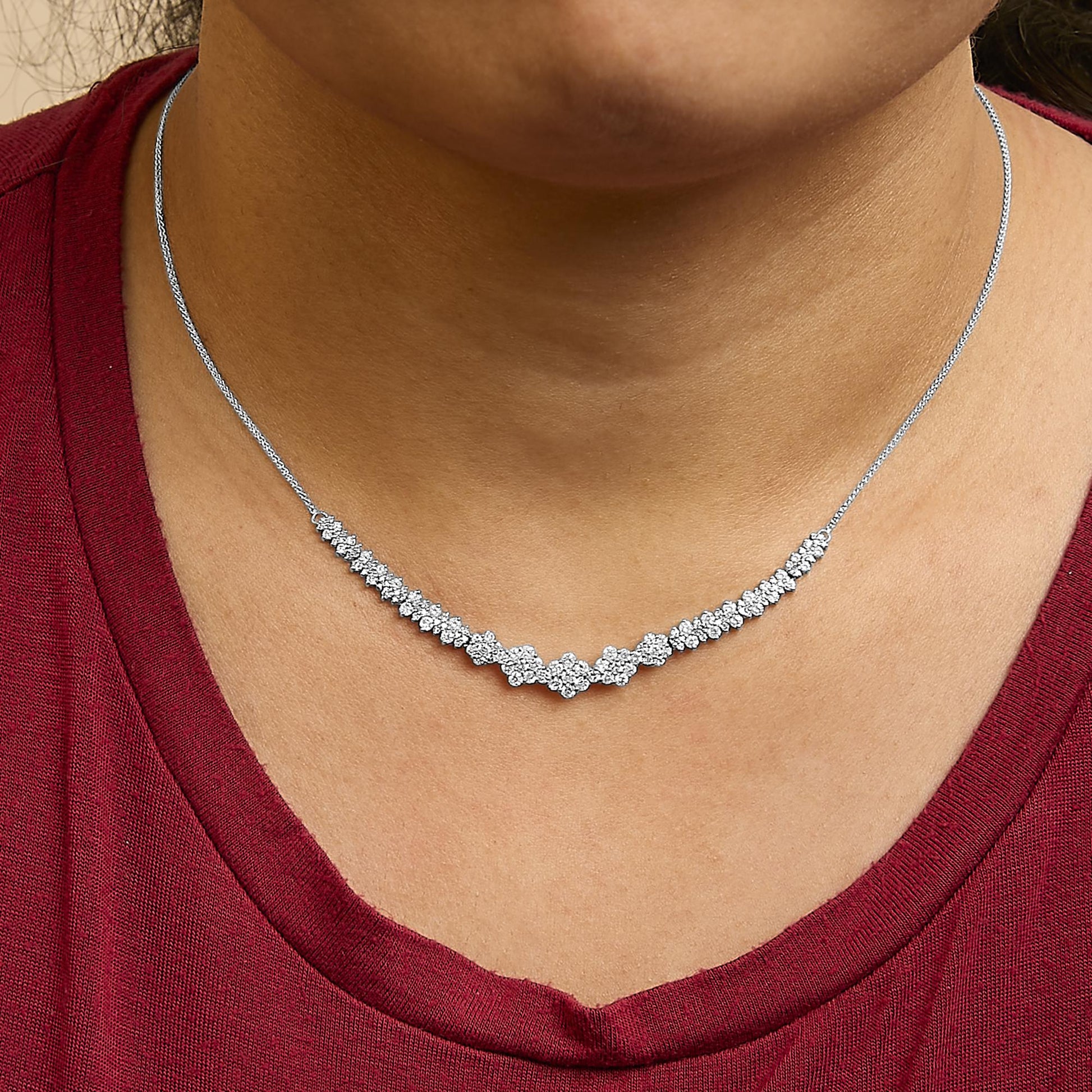 Close-up front view of a white metal necklace with round white gemstones in a shared prong setting, shown worn on a model.
