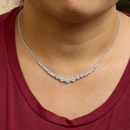 Close-up front view of a white metal necklace with round white gemstones in a shared prong setting, shown worn on a model.