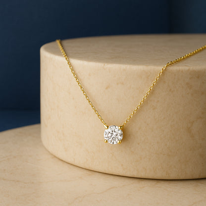 Yellow necklace with a round white gemstone in a four-prong setting, shown at a close-up angle on a beige stone pedestal.