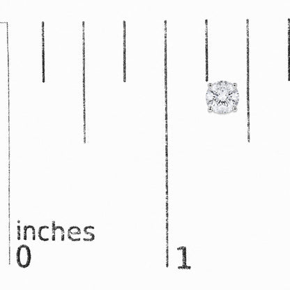 Close-up front angle of a pair of white stud earrings featuring round white gemstones in a four-prong setting, shown on a measurement scale.