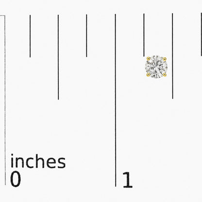 Close-up of a single yellow metal stud earring with a round white gemstone in a four-prong setting, shown on a scale with inch markings, captured from a top-front angle.