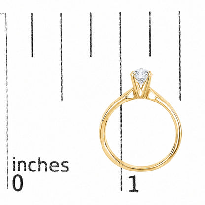 Close-up front angle of a yellow ring with a round white gemstone set in a four-prong setting, shown on a scale.
