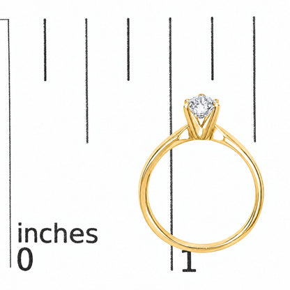 Yellow metal ring with an intersecting band design and a round white gemstone in a four-prong setting, shown on a scale from a front angle.