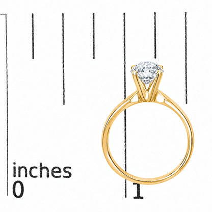 Close-up front view of a yellow metal ring with a round white gemstone set in a four-prong setting, shown on a scale.