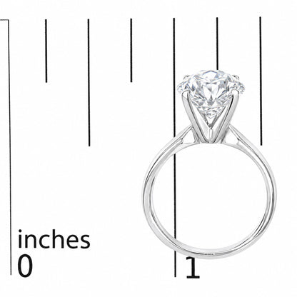 Close-up of a white metal ring with a single round white gemstone in a 4-prong setting, shown on a scale from the side angle.