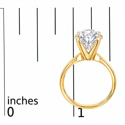 Close-up front angle of a yellow metal ring with a round white gemstone in a four-prong setting, shown on a measurement scale.
