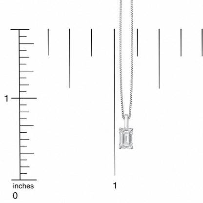 Close-up front view of a white metal necklace with a vertical emerald-shaped white gemstone pendant, shown on a scale.