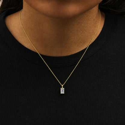 Close-up front view of a yellow metal necklace with a rectangular white gemstone in a 4-prong setting, shown worn on a model.