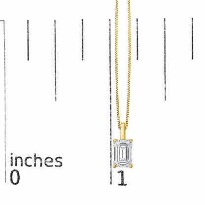 Close-up front view of a yellow necklace chain with a pendant featuring a single emerald-shaped white gemstone in a four-prong setting, shown on a scale.