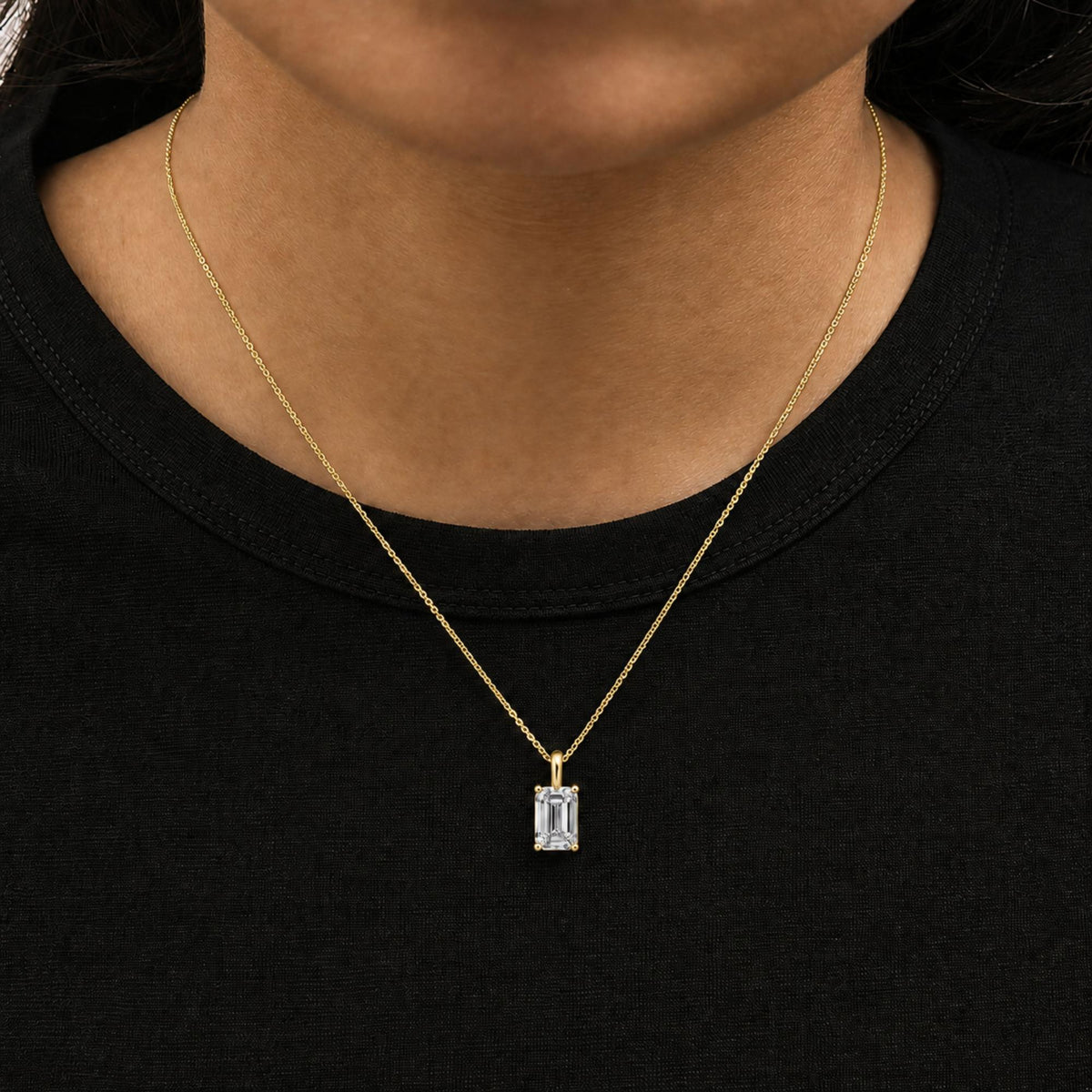 Close-up front view of a model wearing a yellow necklace with an emerald-shaped white gemstone pendant in a 4-prong setting.