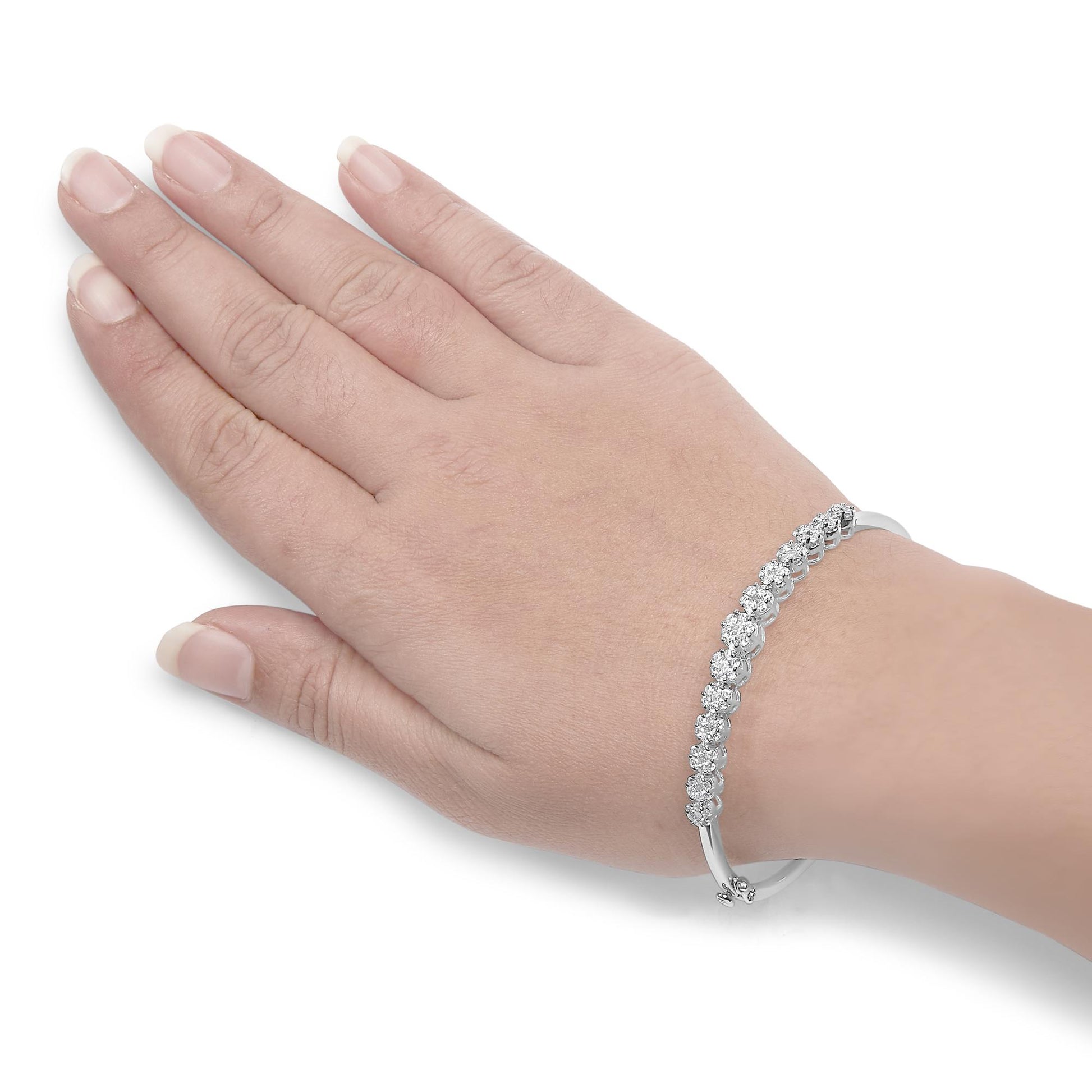 White metal bracelet with round white gemstones in prong settings, worn on a model's wrist, shot from above.