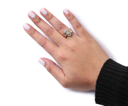 Close-up front angle of a two-toned ring with round white gemstones in prong settings and baguette white gemstones in channel settings, worn on a model's finger.