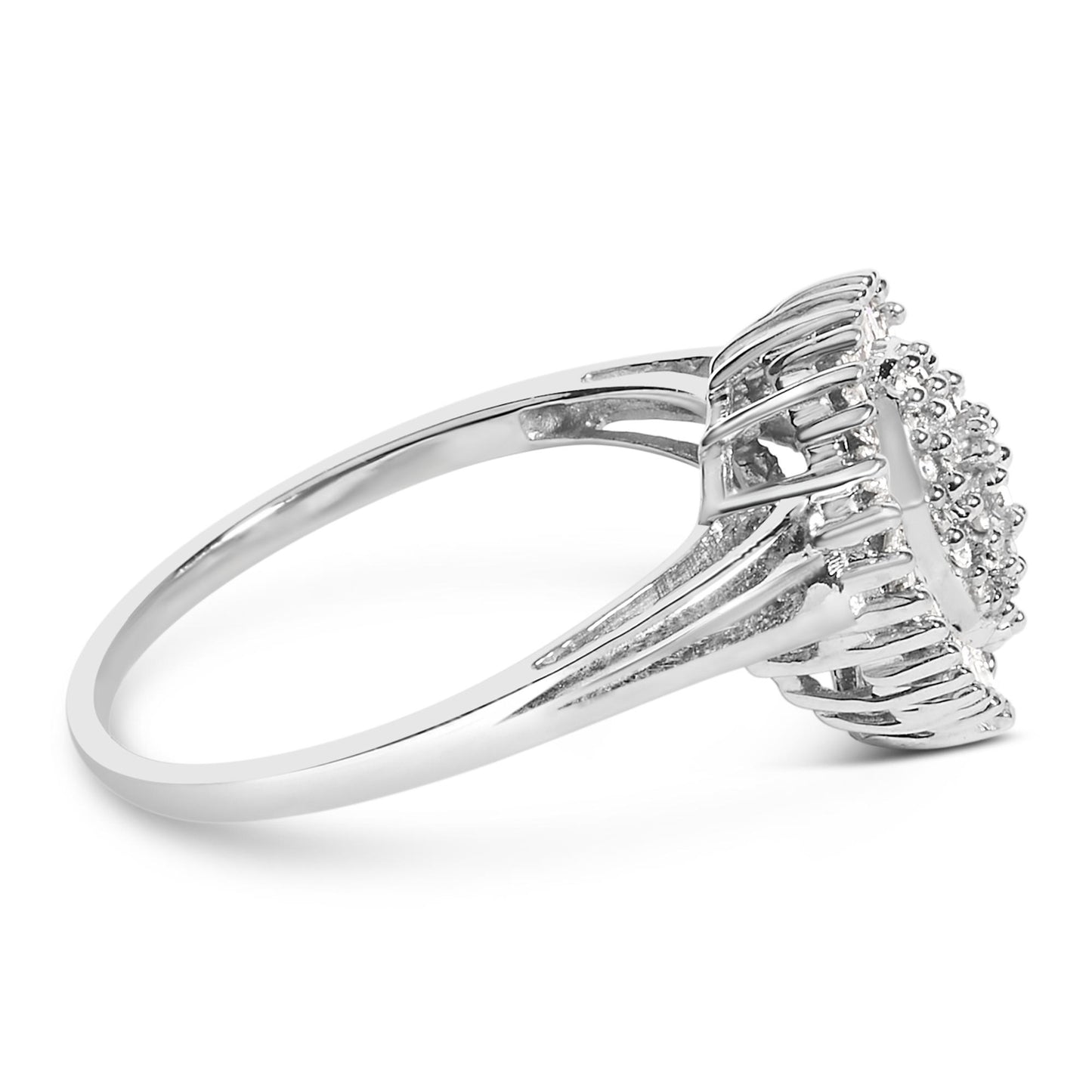 Side angle view of a white metal ring with a raised cluster of round white gemstones in prong settings surrounded by a frame of baguette-shaped white gemstones in channel settings.