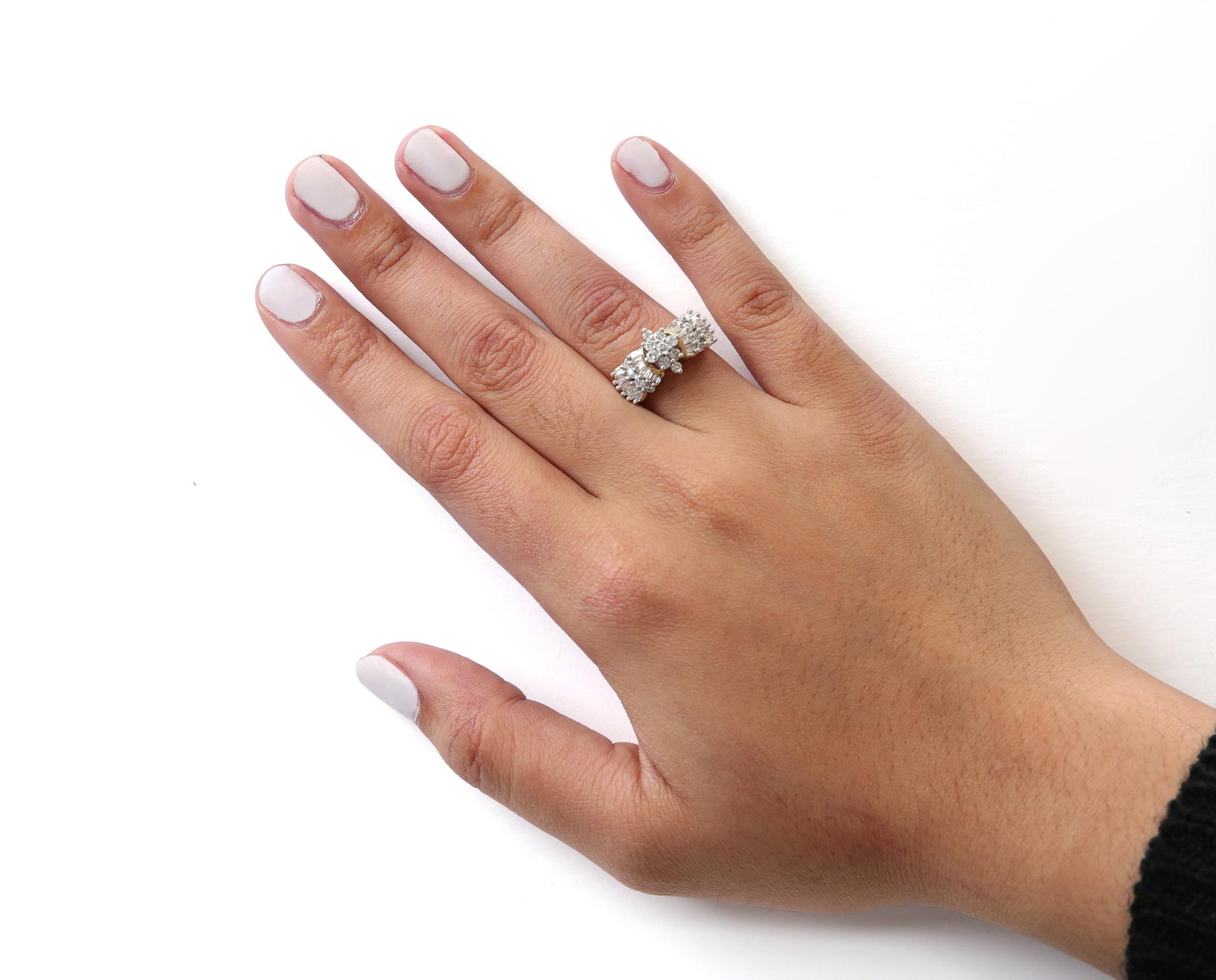Close-up front angle of a hand wearing a yellow metal ring with round and baguette-shaped white gemstones in prong settings.