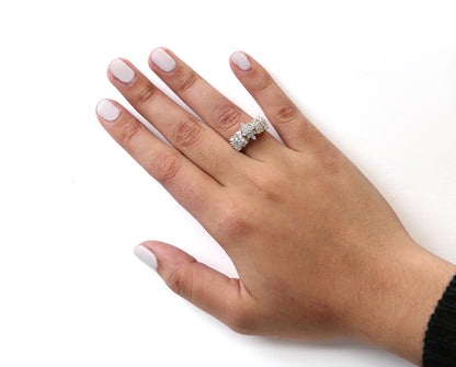 Close-up front angle of a hand wearing a yellow metal ring with round and baguette-shaped white gemstones in prong settings.