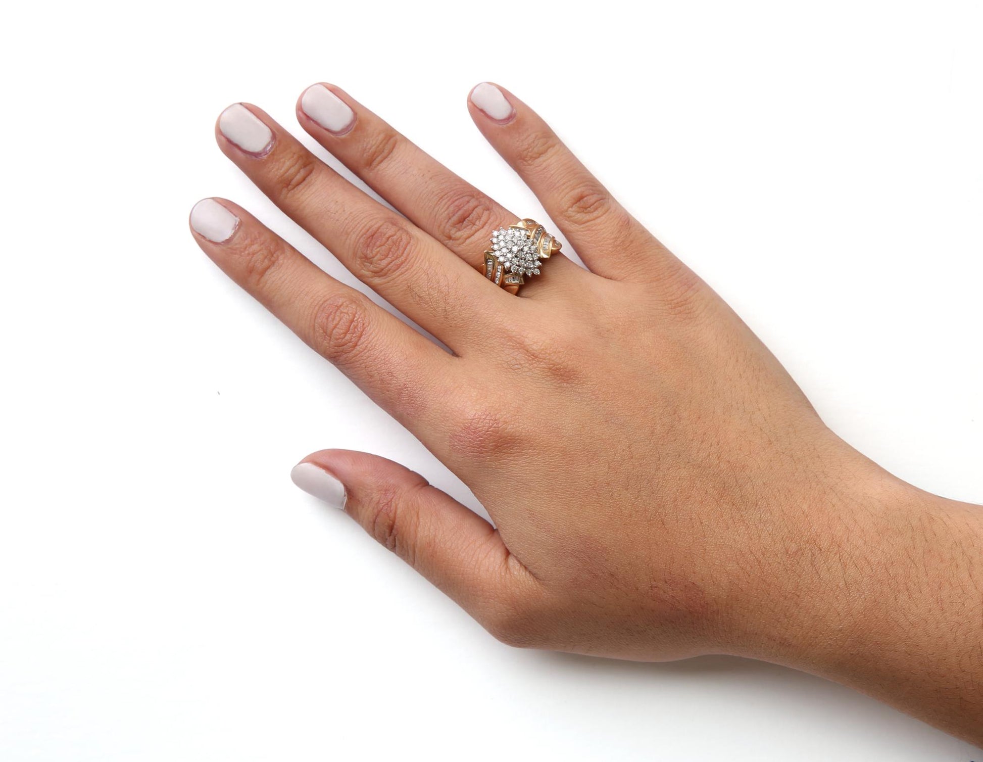 Yellow metal ring with round white gemstones in prong setting and baguette white gemstones in channel setting, worn on a model's finger, top-down angle.