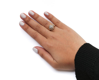 Yellow metal ring with round and baguette shaped white gemstones, worn on finger, shown from top angle.